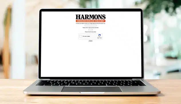 Laptop on a kitchen counter showing the Harmons gift card balance lookup page