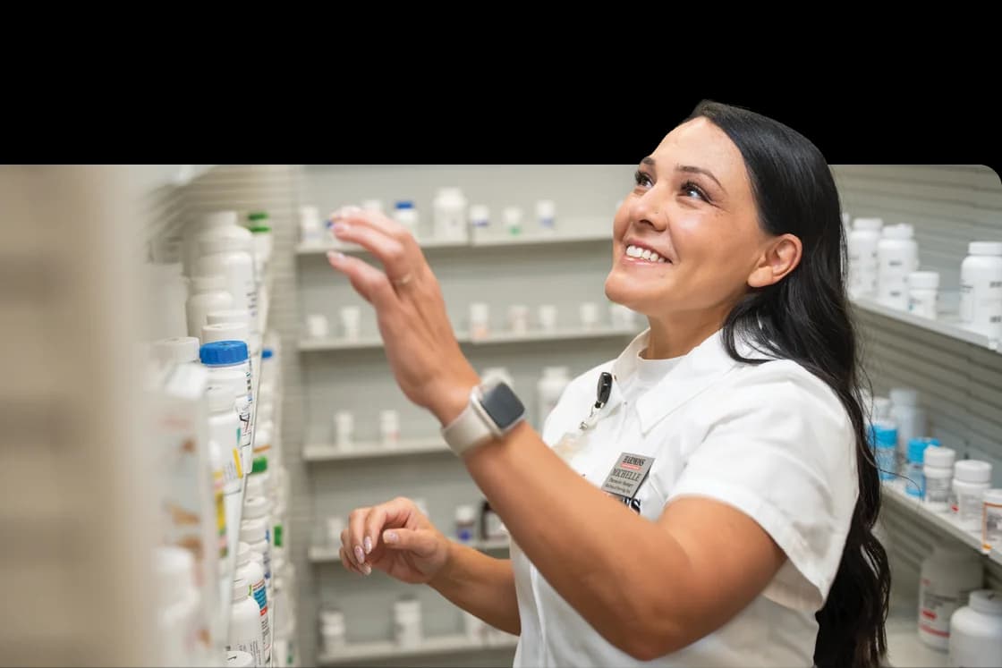 Harmons pharmacist reaching for a prescription bottle on the pharmacy shelf