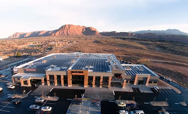 Aerial view of solar panels on the roof of the Harmons Santa Clara store with red rock cliffs behind